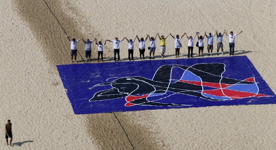 Participants in Brazil’s Five Years Too Many campaign line up behind a mural on Copacabana Beach in Rio de Janeiro on 5 May 2013.